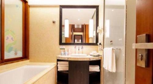 a bathroom with a sink and a tub and a mirror at Ocean Spring Metropark Hotel Zhuhai in Zhuhai