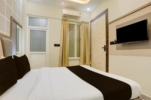 a bedroom with a white bed with a tv on the wall at Super Hotel O Maharshi Valmiki International Airport Formerly Gaurav Inn in Faizābād