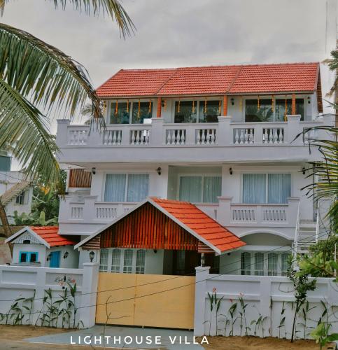 a large white building with a red roof at Lighthouse Villa in Cherai Beach