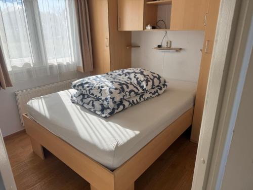 a bed with a pillow on it in a room at Chalet op Ameland voor 5 personen in Buren