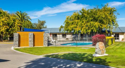 a house with a swimming pool and trees at Cherylea Motel in Blenheim