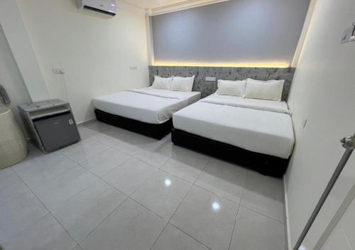 a hotel room with two beds and a tv at D'Lima Beach Inn in Pantai Cenang