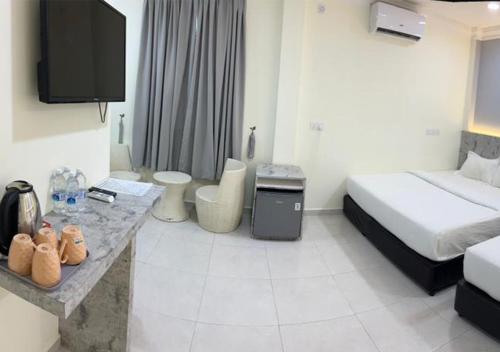 a hotel room with a bedroom with a bed and a tv at D'Lima Beach Inn in Pantai Cenang