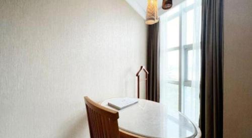 a table and a chair in a room with a window at Excemon Beach Hotel Beihai in Beihai