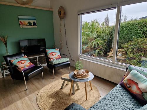 a living room with a couch and chairs and a large window at Relax, rust, strand, privé huisje in Lemmer