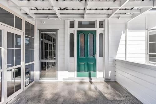 a green door on a white house with windows at Deluxe Twin Room at Wolfe Street in Whangarei