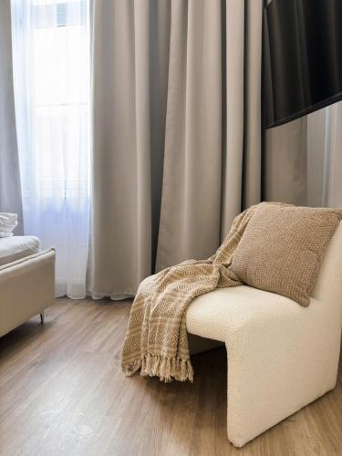 a room with a white chair with a blanket on it at TINTURA by BAST - Wanna, Antresola, OFF Piotrkowska, EC1 ,Stajnia Jednorożca, Winda, Parking na Terenie, Orientarium, Hopa Lupa, ATLAS ARENA in Łódź