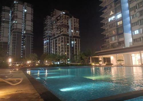 a large swimming pool at night with tall buildings at Palmera Residensi in Kajang