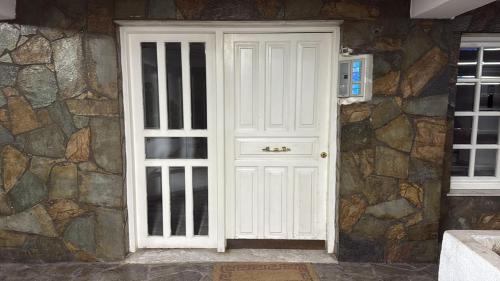 eine weiße Tür an einer Steinmauer mit einer Mikrowelle in der Unterkunft Lampsakou1 in Piräus
