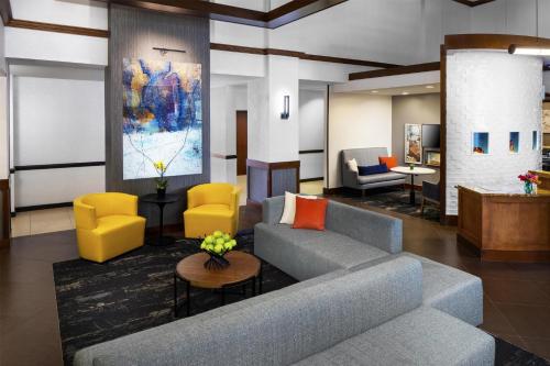 a living room with a couch and yellow chairs at Hyatt Place Greenville/Haywood in Greenville