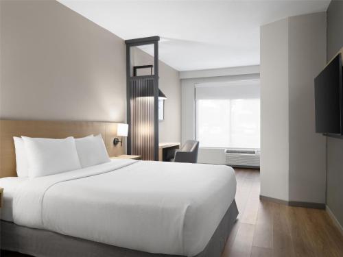 a hotel room with a large white bed and a desk at Hyatt Place Greenville/Haywood in Greenville
