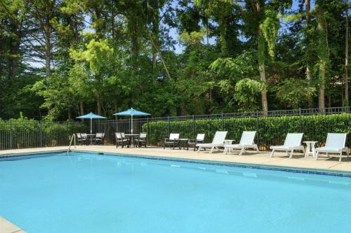 a swimming pool with chairs and umbrellas next to a fence at Hyatt Place Greenville/Haywood in Greenville