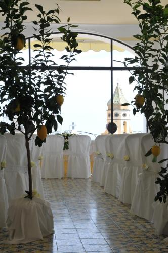 a row of tables with white chairs and a tree at Tramonto d'Oro in Praiano