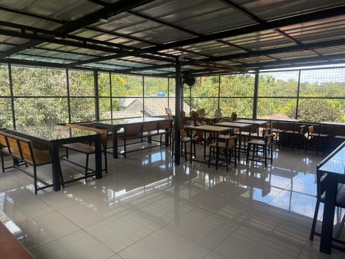 a dining room with tables and chairs and windows at Empire One Bedroom with Common Pool in Wayanad