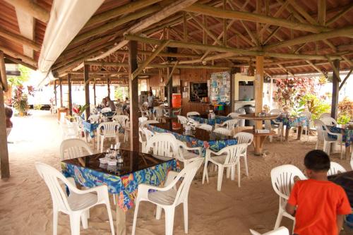 a dining room with white chairs and tables and people at Hospedaje Yarisnori in Bocas del Toro