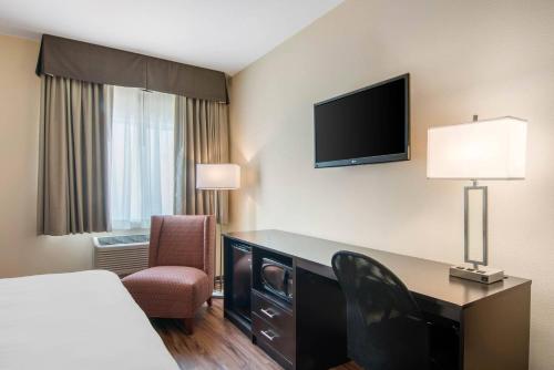a hotel room with a desk and a tv at Econo Lodge Inn & Suites Springfield Main Street in Springfield