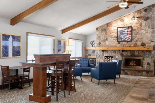 a living room with a stone fireplace and a table and chairs at AmericInn by Wyndham Alexandria in Alexandria