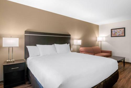 a bedroom with a large white bed and a chair at Econo Lodge Inn & Suites Springfield Main Street in Springfield