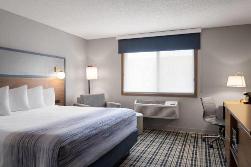 a hotel room with a large bed and a window at AmericInn by Wyndham Alexandria in Alexandria
