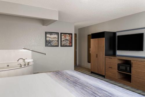 a hotel room with a bed and a flat screen tv at AmericInn by Wyndham Alexandria in Alexandria