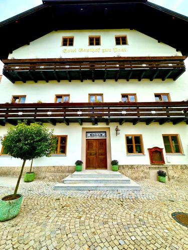 a white building with a door and a tree at Hotel Bergen Zur Post by Rikas Hotels in Bergen