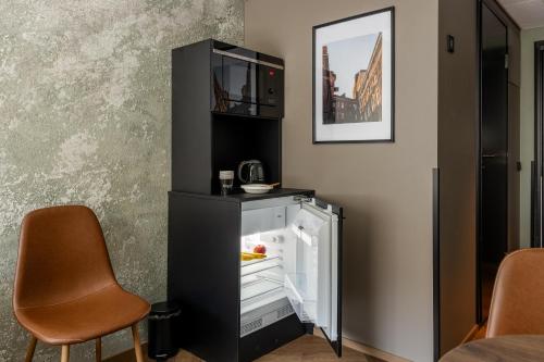 a black refrigerator with its door open and two chairs at H28 - Hotel, Apartments and Suites by UHANDA in Tampere