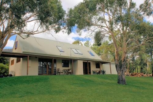 Una casa blanca con un árbol delante. en Otago Cottage, en Hobart