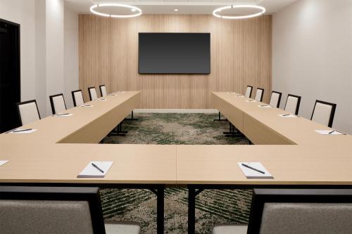 a conference room with long tables and chairs and a screen at Hyatt Place Montreal Airport in Dorval