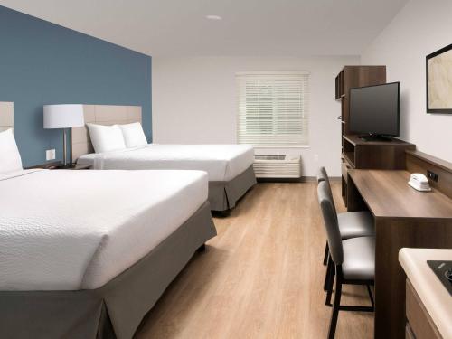 a hotel room with two beds and a desk at WoodSpring Suites Rogers Bentonville in Rogers