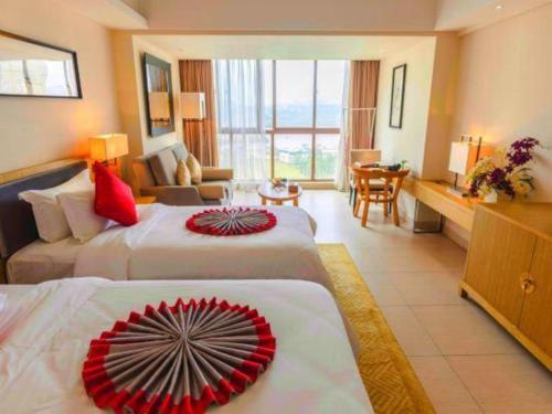 a hotel room with two beds and a living room at Da Peng Zhongzhou Hotel in Haikou