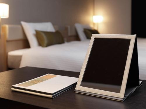 a table with a book on a table with a bed at Mitsui Garden Hotel Kyoto Shinmachi Bettei in Kyoto