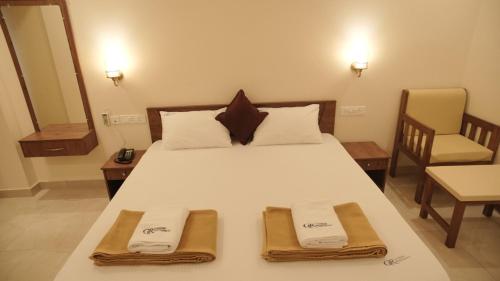 a bedroom with a large white bed with two towels at Ganesh Residency 