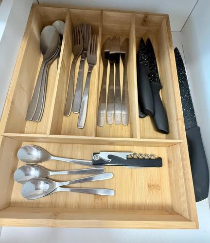 a wooden tray with utensils in a drawer at Family Apartman Michalovce in Michalovce