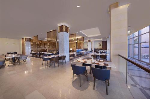 延布Kempinski Hotel & Resort Sariya Yanbu Red Sea的建筑物内有桌椅的餐厅