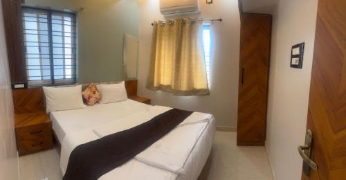 a bedroom with a white bed and a window at MSK Homestay Service Apartments in Hubli