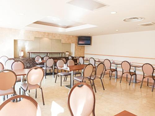 a conference room with tables and chairs and a screen at Tetora Higashimuroran in Muroran