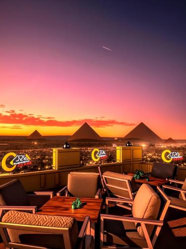 a rooftop bar with chairs and a view of the pyramids at Pyramids Nomad View Hotel in Cairo