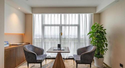 a room with two chairs and a table and a window at Grand Metropark Hotel Chongqing in Chongqing