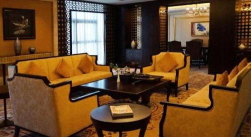 a living room with yellow couches and a table at Grand Metropark Hotel Chongqing in Chongqing