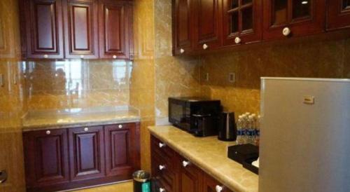 a kitchen with wooden cabinets and a refrigerator at Grand Metropark Hotel Chongqing in Chongqing