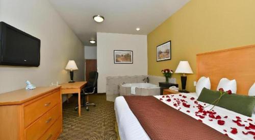 a hotel room with a bed and a desk and a television at Best Western Plus Guymon Hotel and Suites in Guymon