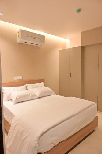 a bedroom with a white bed with a air conditioner at Saba's Courtyard in Kolachel