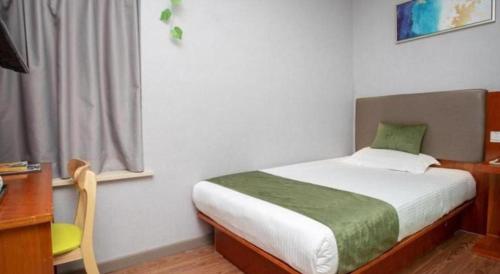 a bedroom with a bed with a desk and a window at Vatica Shanghai Jiading District Anting Metro Station Moyu Road Hotel in Shanghai