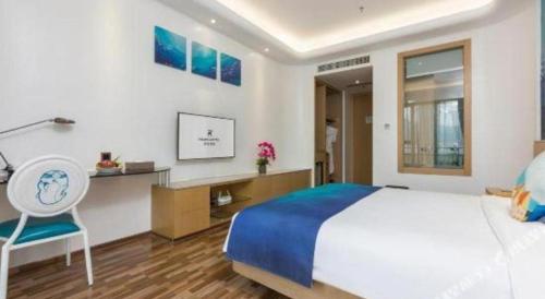 a bedroom with a bed and a desk and a chair at Beluga Sanya Discovery Ocean World in Shangsimacun