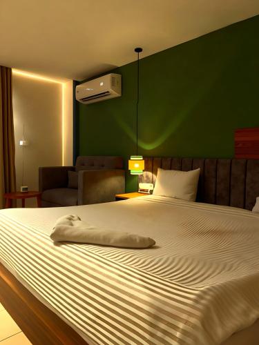 a bedroom with a large white bed with a green wall at Pyramids Nomad View Hotel in Cairo