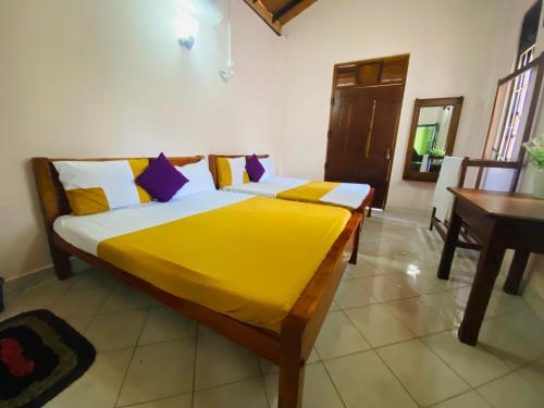 a bedroom with two beds with yellow sheets and a table at GB Royal Stay Nuwara Wewa in Nikawatawana