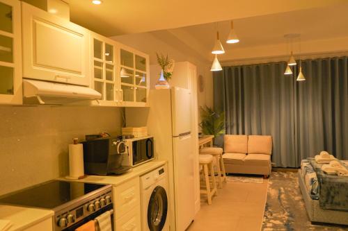 a kitchen with a microwave and a living room at Marjan Lux Homes in Ras al Khaimah