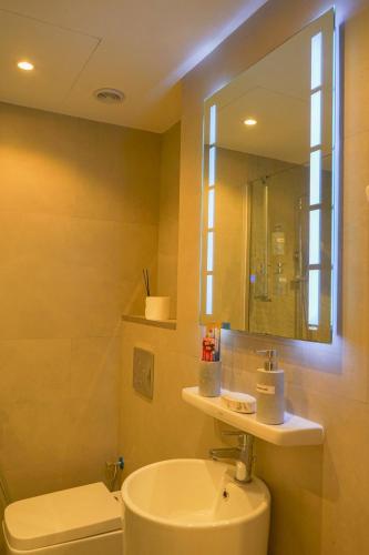 a bathroom with a toilet and a sink and a mirror at Marjan Lux Homes in Ras al Khaimah