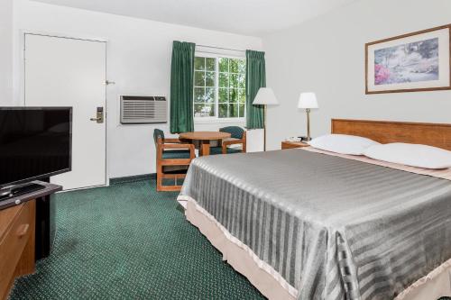 a hotel room with a bed and a flat screen tv at Travelodge by Wyndham Grants Pass in Grants Pass