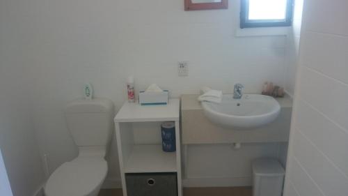 a white bathroom with a toilet and a sink at Aroa Beachside Resort in Rarotonga
